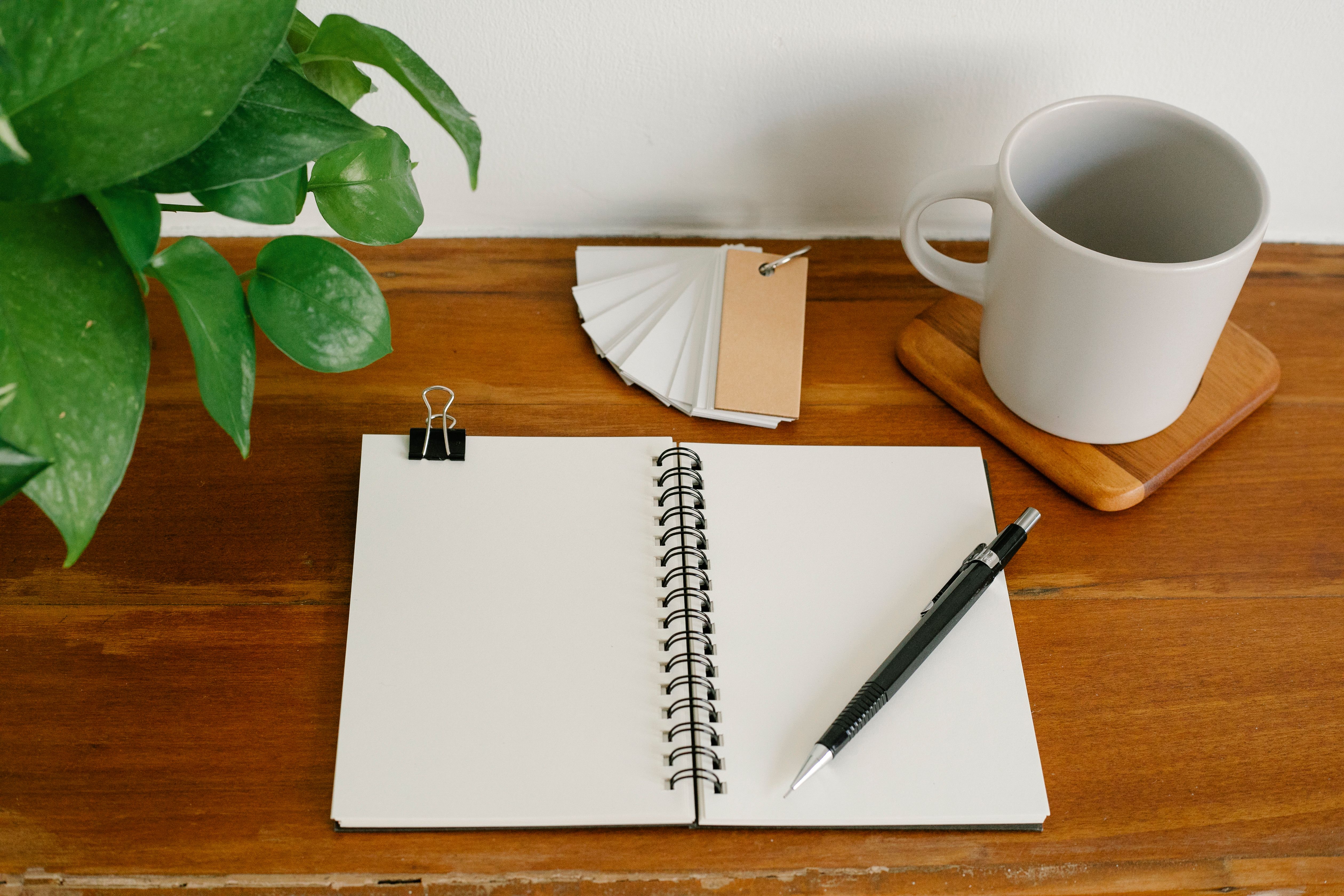 Open notebook and pen on a wooden desk, a quiet workspace for reviewing long-term investment goals