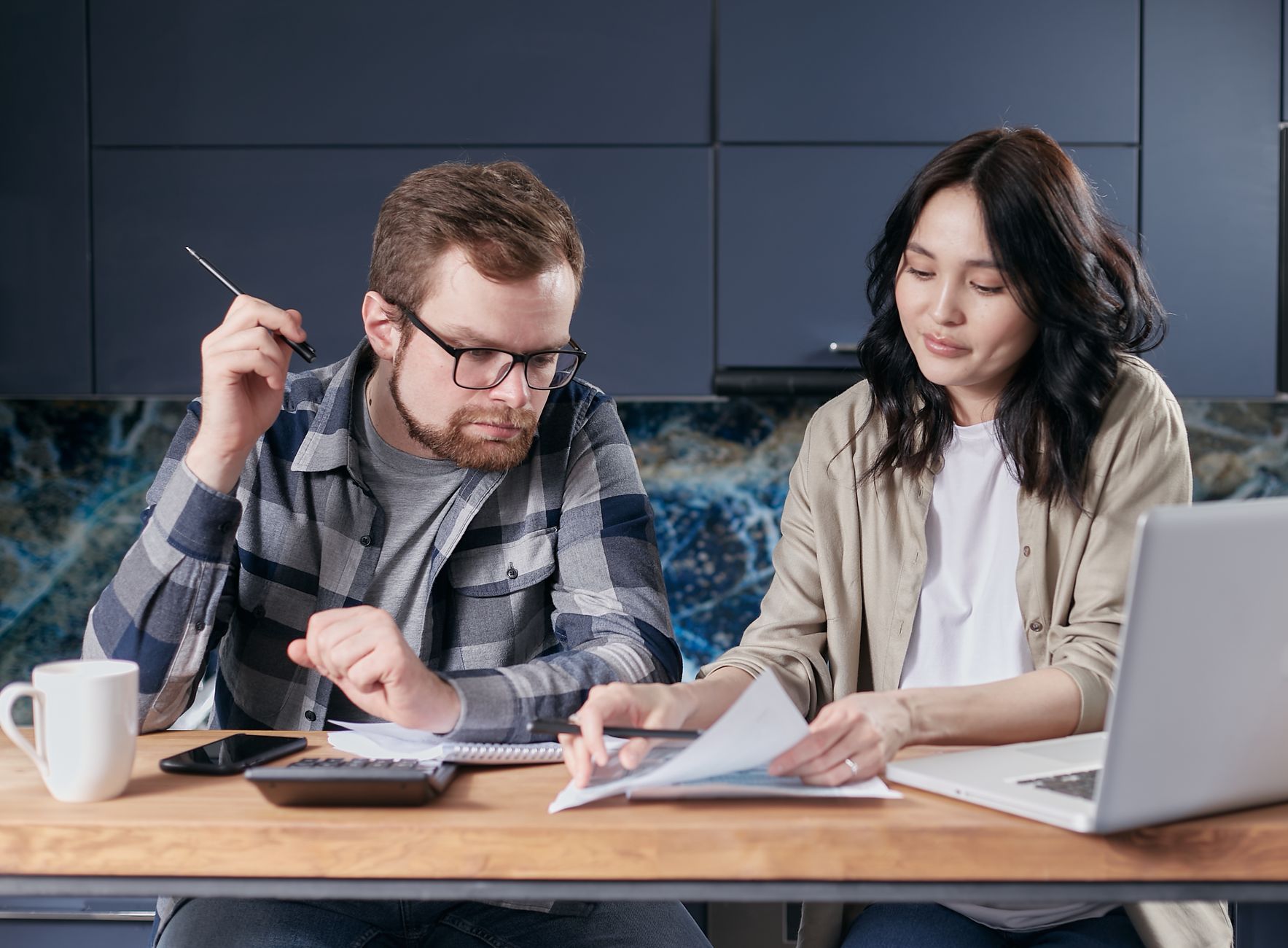 A couple reviewing a paper household budget together beside a calculator